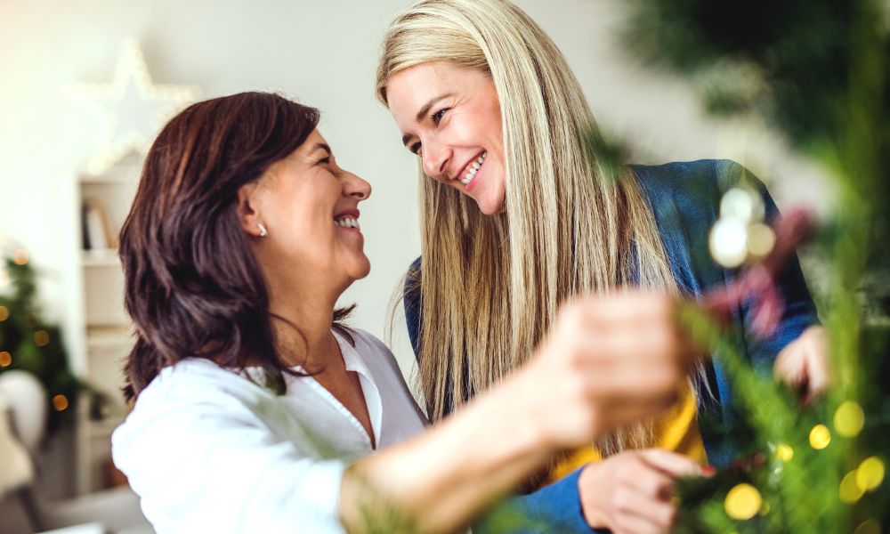 older mum and daughter hanging Christmas decorations